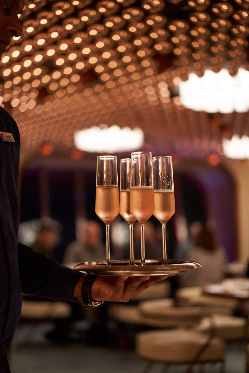 A tray of champagne flutes is carried to a table at The Wake restaurant.